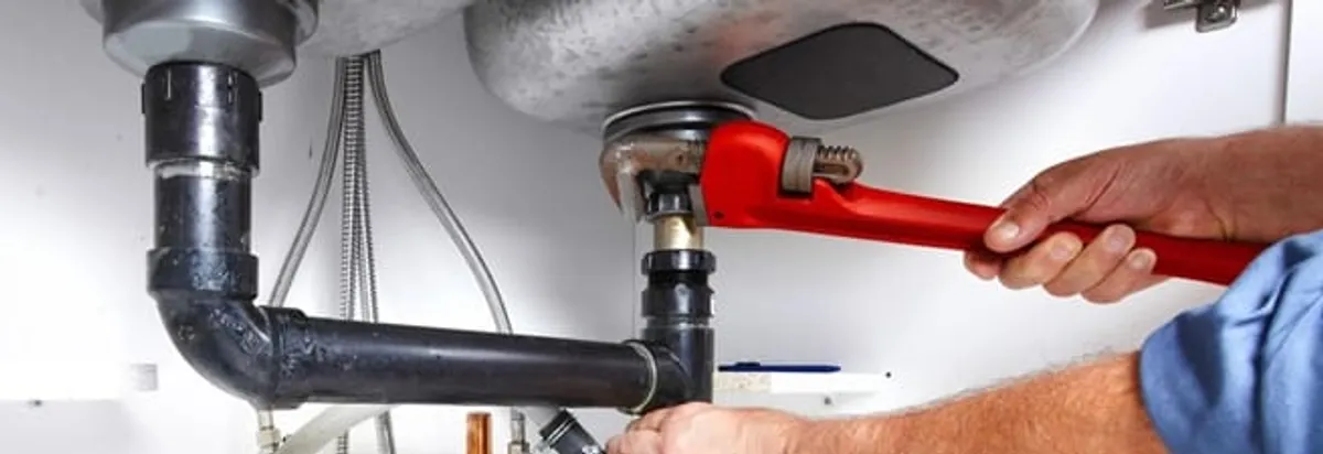 Garbage disposal repair technician tightening the sink drain and disposal connection in Chula Vista, CA