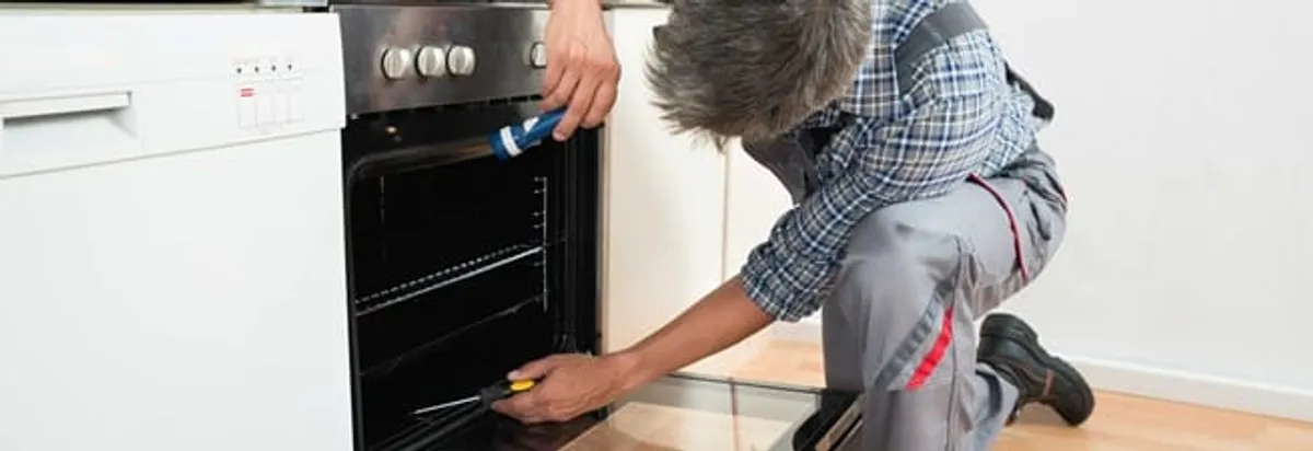 Oven repair technician inspecting and servicing an electric oven in Chula Vista, CA