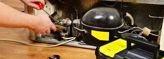 Refrigerator repair technician fixing the compressor and wiring in Chula Vista, CA